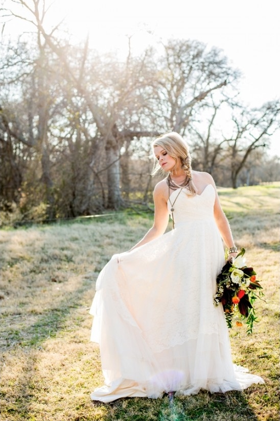 Bride in lace dress holds bouquet outdoor wedding