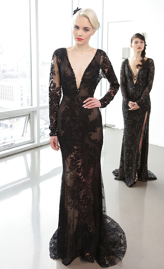 Two models in elegant black lace evening gowns posing inside