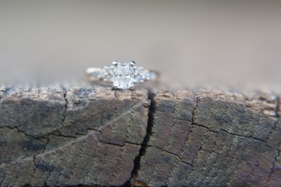 Radiant cut diamond ring on textured wood surface
