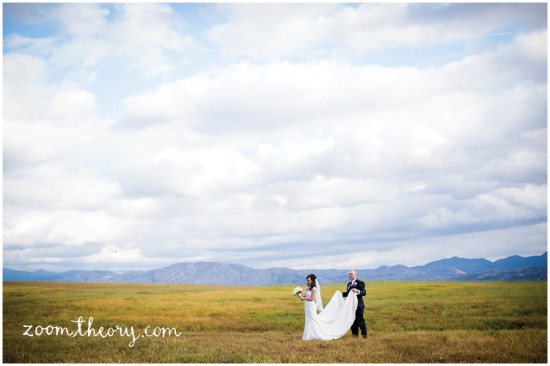 Bride and groom holding wedding dress on a grassy field