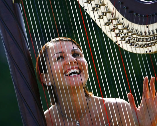 Smiling woman playing a harp, joyful music concept