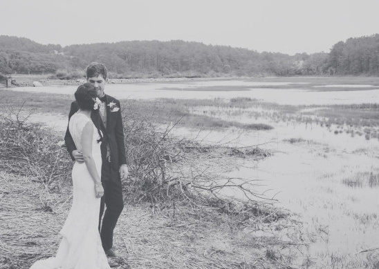 Bride and groom embracing by a tranquil waterscape on their wedding day