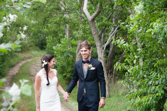 Bride and groom holding hands in a forest pathway on their wedding day
