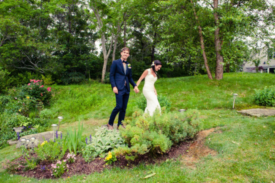 Bride and groom holding hands, walking through garden after wedding