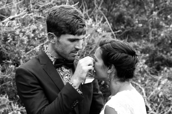 Groom offering drink to his bride in a black and white wedding photo