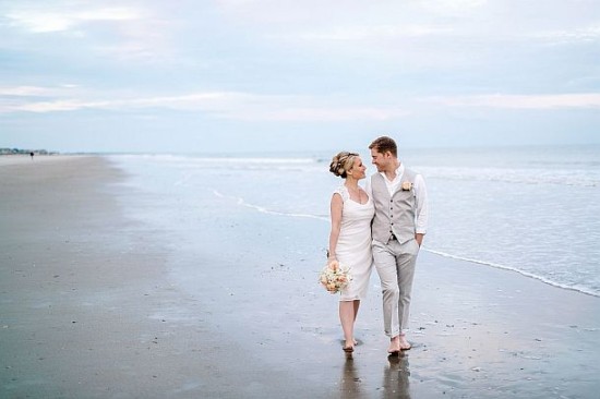 Newlyweds strolling on a beach after their beautiful seaside wedding