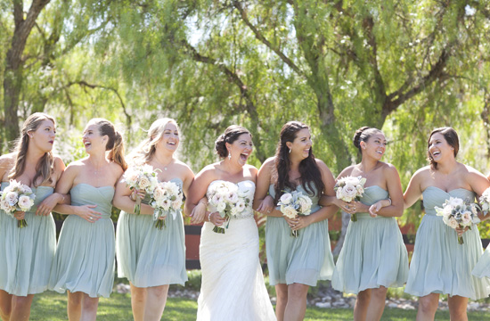 Bridesmaids laughing with bride on a sunny day, holding hands