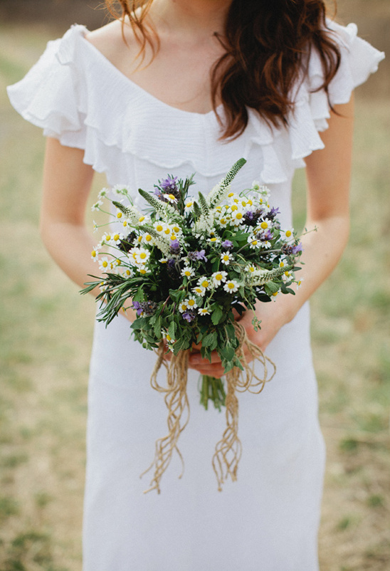 Woman in white dress holding a bouquet of wildflowers