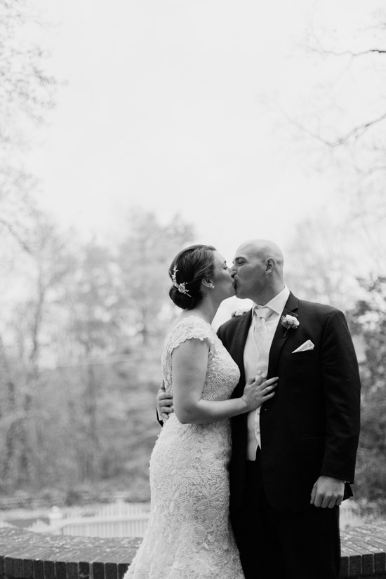 Newlyweds share a romantic kiss on their wedding day in black and white