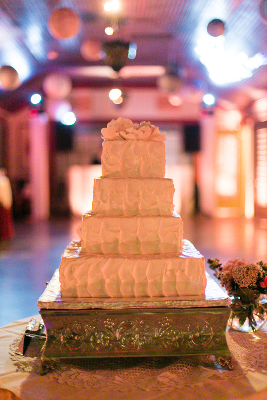 Elegant four-tiered wedding cake with floral topping at a reception