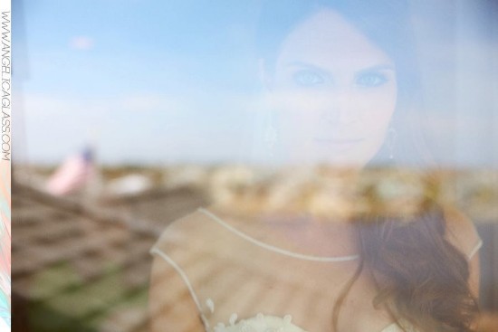 Bride's reflection through a window gazing outside on her wedding day