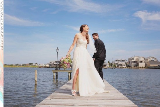 Bride and groom laughing on a pier, enjoying a sunny wedding day