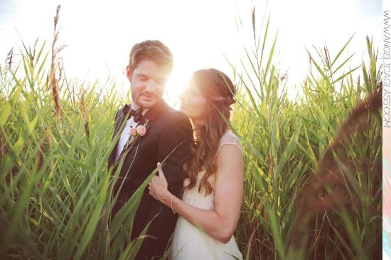 Elegant wedding couple in field of tall grass, backlit by the sun