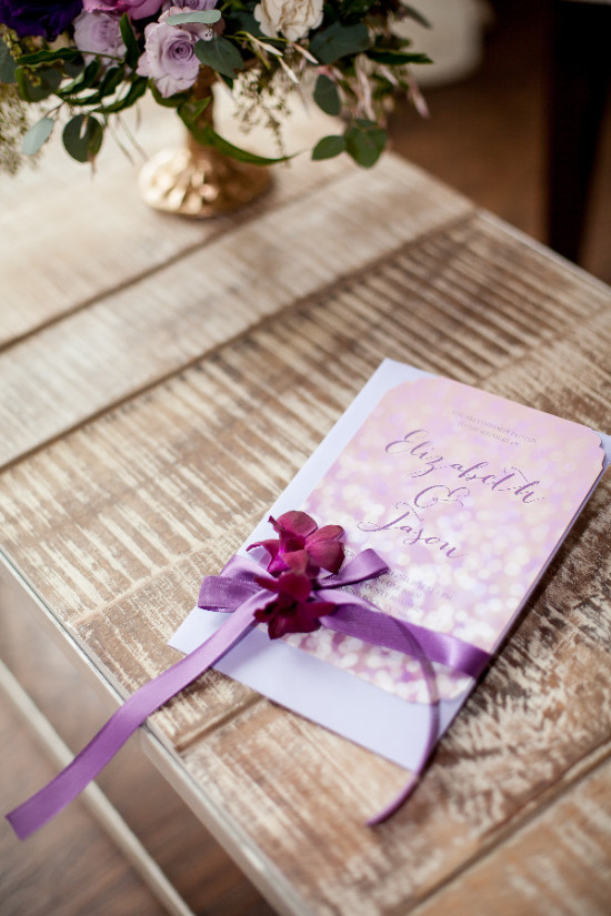 Wedding program with purple ribbon and floral centerpiece