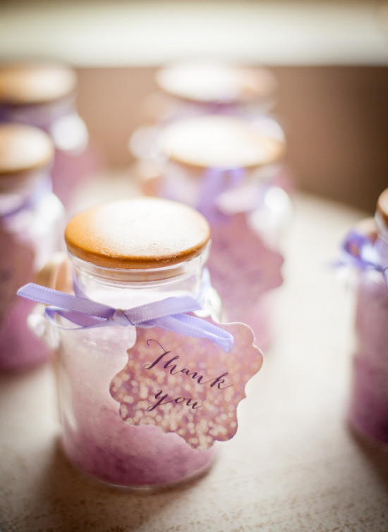 Wedding favors featuring small jars of lavender bath salts with a thank you tag