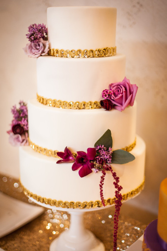 Elegant four-tiered wedding cake decorated with gold and flowers