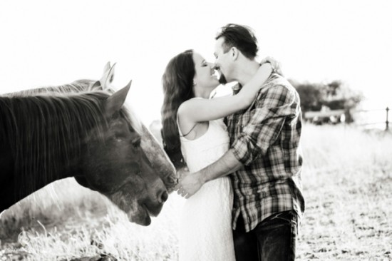 Couple embracing with horse in black and white field