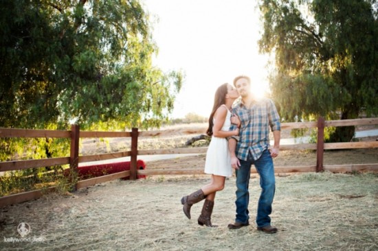 Couple kissing in golden hour, with wooden fence in the background