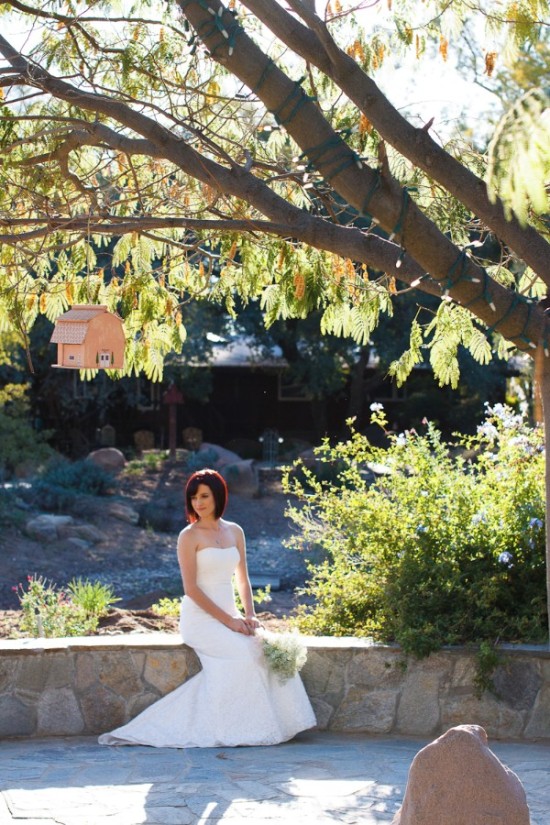 Bride in a white dress, posing on a stone wall outside