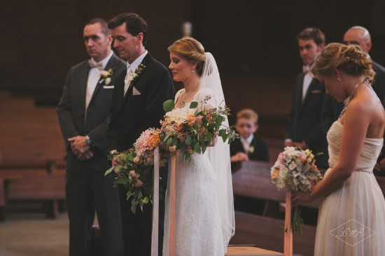 Bride and groom at the altar with wedding bouquets and guests present