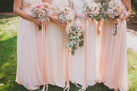 Bridesmaids holding bouquets, wearing blush dresses, at a wedding