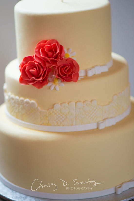 Three-tiered yellow cake with red roses decoration for a wedding