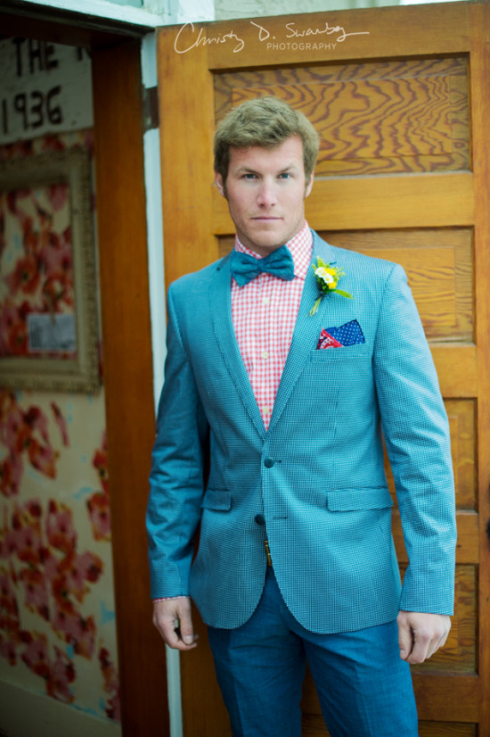 Stylish groom in blue suit and bow tie posing for a photo