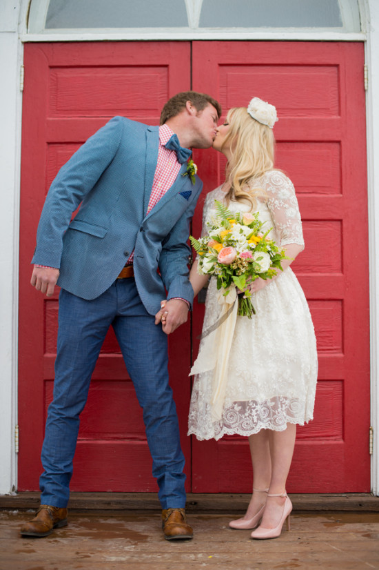 Happy couple kissing on their wedding day in front of red doors