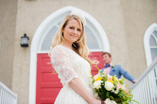 Beautiful bride in lace dress holding flowers with groom behind