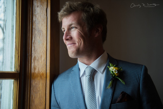 Handsome groom in a blue suit smiling near a window