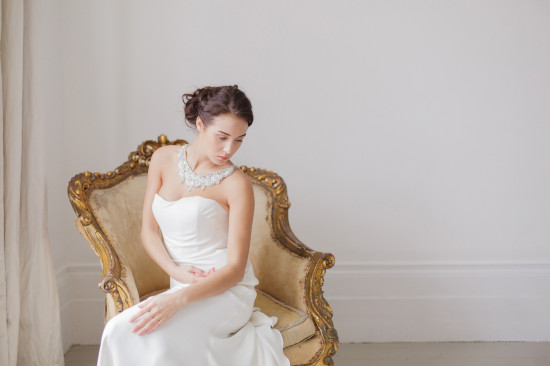 Elegant bride in white dress sits on a vintage golden chair