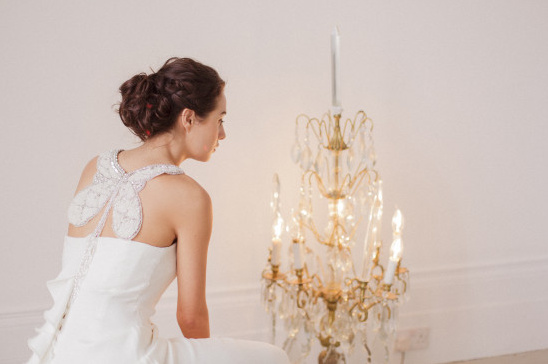 Elegant bride in butterfly-backed dress, with chandelier