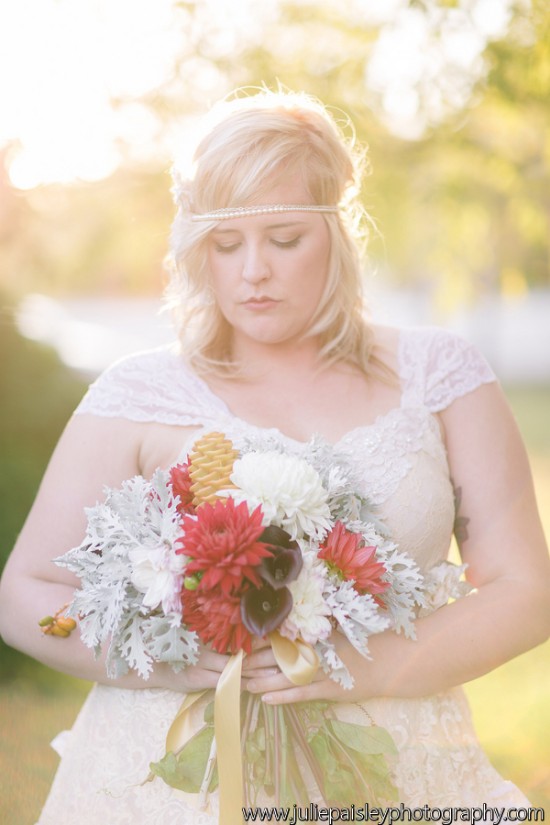 Bride in lace dress holding vibrant fall wedding bouquet