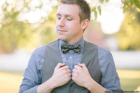 Smiling man in a vest and bowtie adjusting his shirt