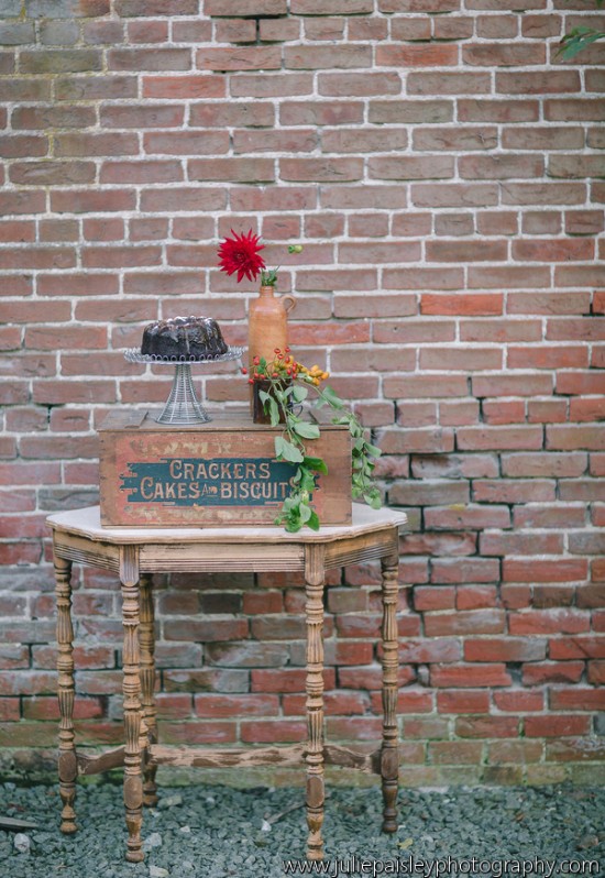 Rustic scene: cake, flowers, and old table against brick wall