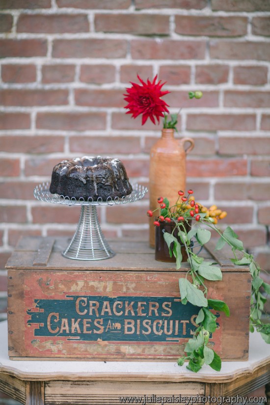 A rustic cake display with flowers and vintage crackers box