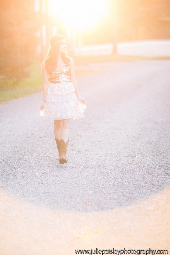 Young woman in dress and boots walking on sunlit path