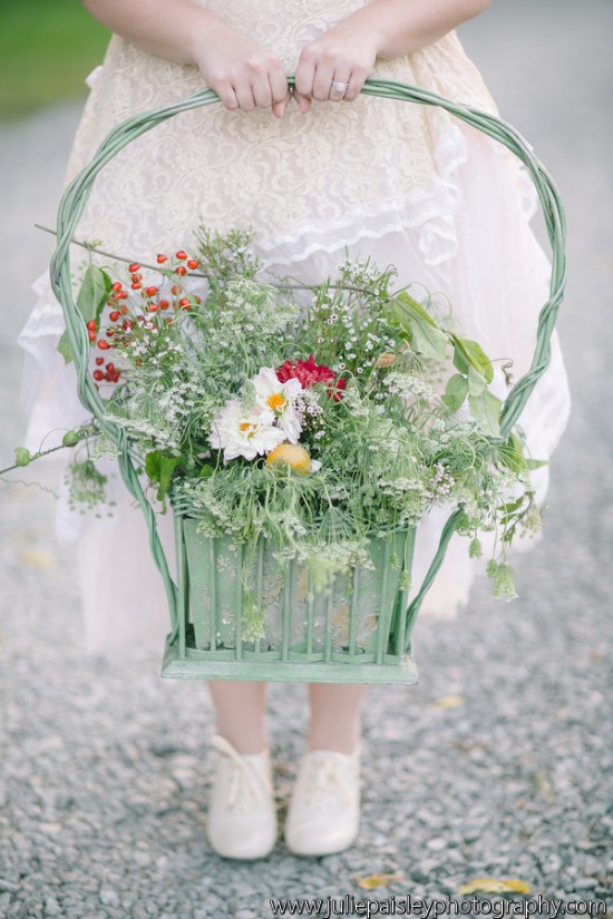 A woman holding a green basket filled with beautiful flowers