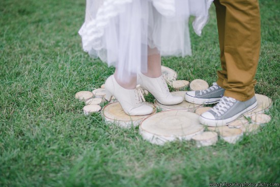 Bride and groom shoes standing on wooden slices in the grass