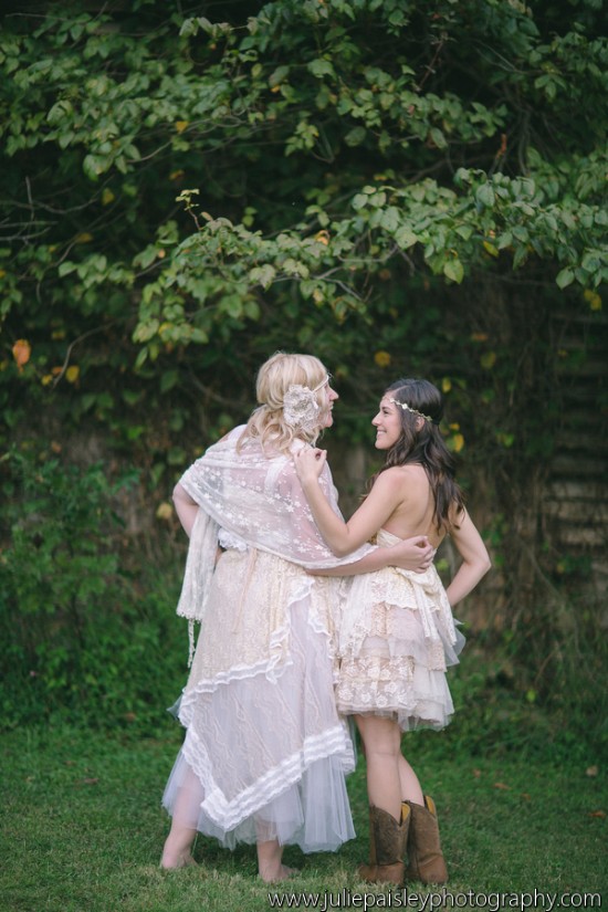 Two boho women embracing each other in a grassy field setting