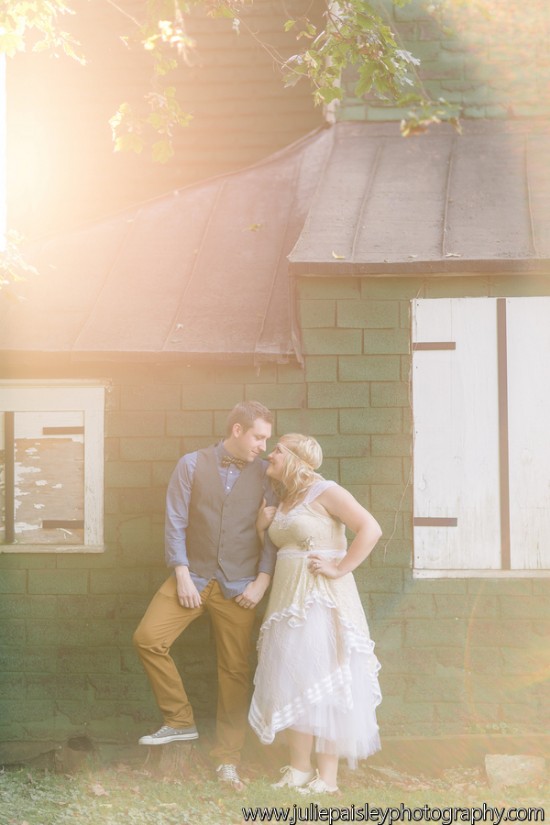 Couple embracing at a whimsical outdoor wedding photoshoot next to green building