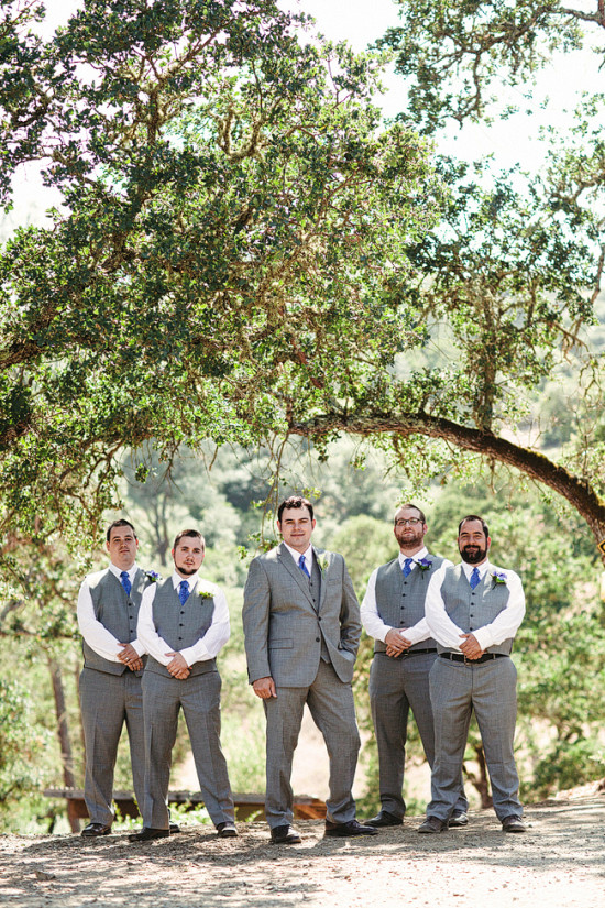 Groomsmen in grey suits posing for a photo in a scenic outdoor setting