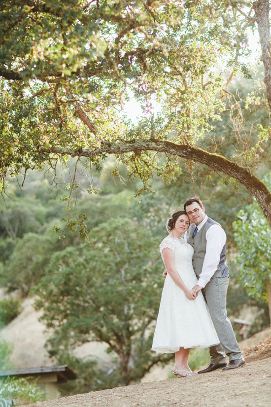 Bride and groom hold hands under a tree on their wedding day