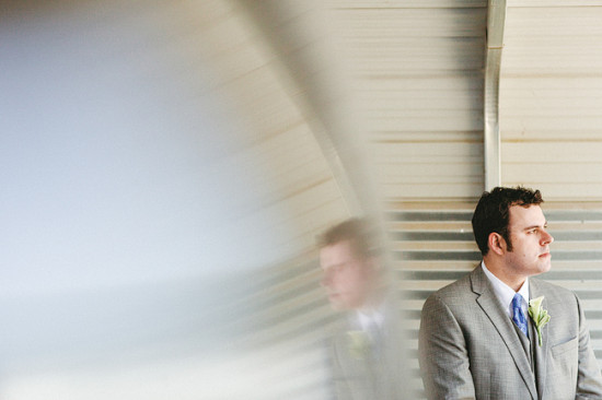 Groom looking thoughtful in his suit with reflection beside him