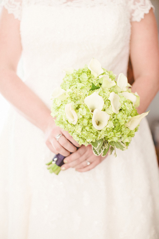 Bride in lace dress holding a green and white bouquet