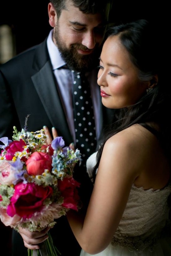 Bride and groom embrace with bouquet at their wedding