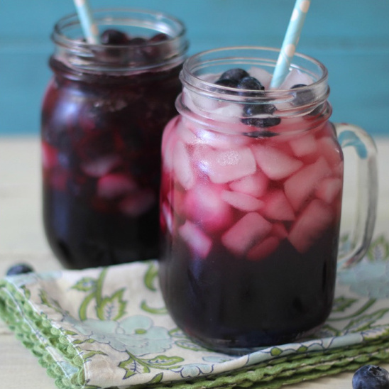 Two refreshing glasses of blueberry lemonade with ice cubes