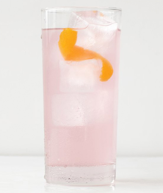 Pink cocktail in a glass with orange peel and ice