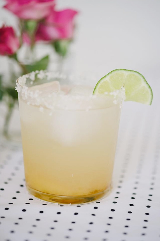 Refreshing margarita cocktail with lime and pink roses background
