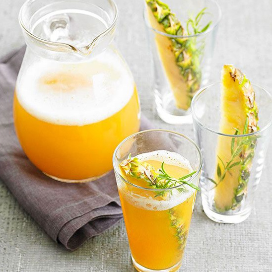 Refreshing pineapple juice with fresh herbs in glasses and a pitcher
